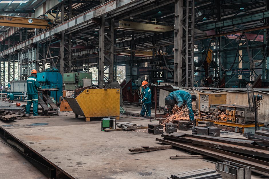 Workers in a metal workshop engaged in active construction and welding tasks.