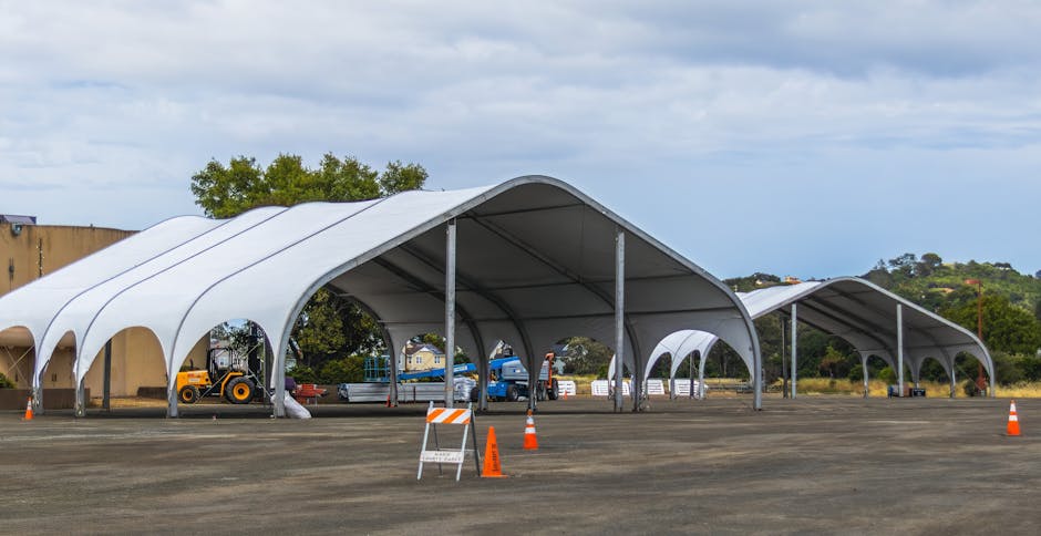 Large outdoor canopies set up for rural events or storage in a countryside field.