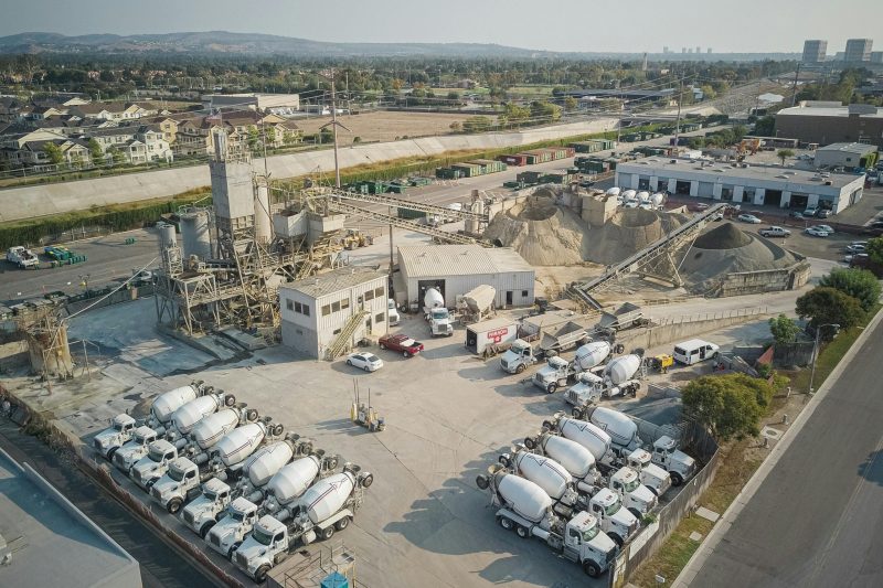 Aerial shot of a bustling cement manufacturing plant with mixer trucks and industrial equipment.